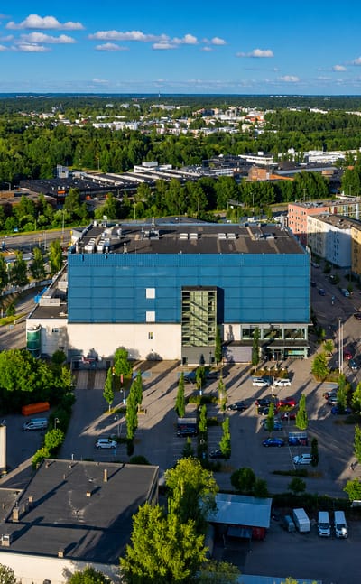 Aerial daytime view of Konala, Helsinki, with commercial buildings, modern apartment blocks and leafy suburban streets.