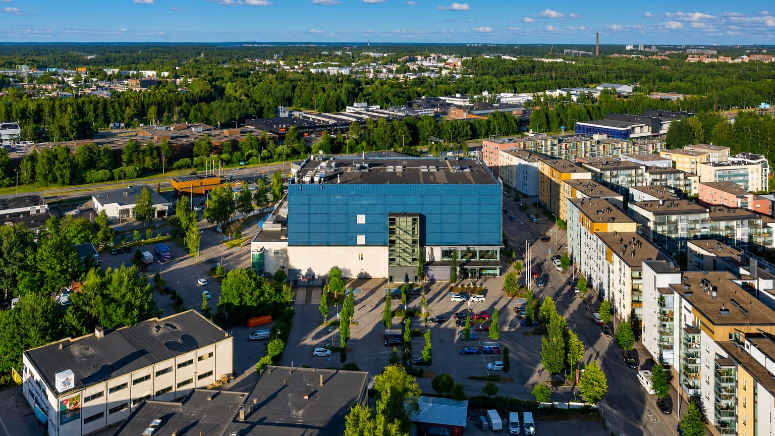 Aerial daytime view of Konala, Helsinki, with commercial buildings, modern apartment blocks and leafy suburban streets.