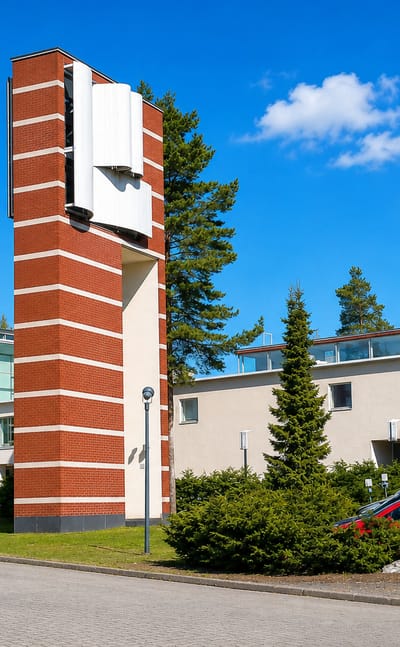 Red-brick modernist church and low white buildings among pines in Kontula, eastern Helsinki.