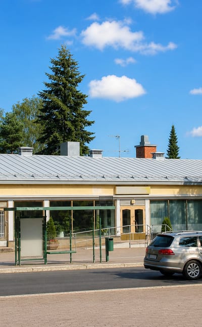 Paloheina's low yellow shopping parade and bus shelter framed by birches in northern Helsinki