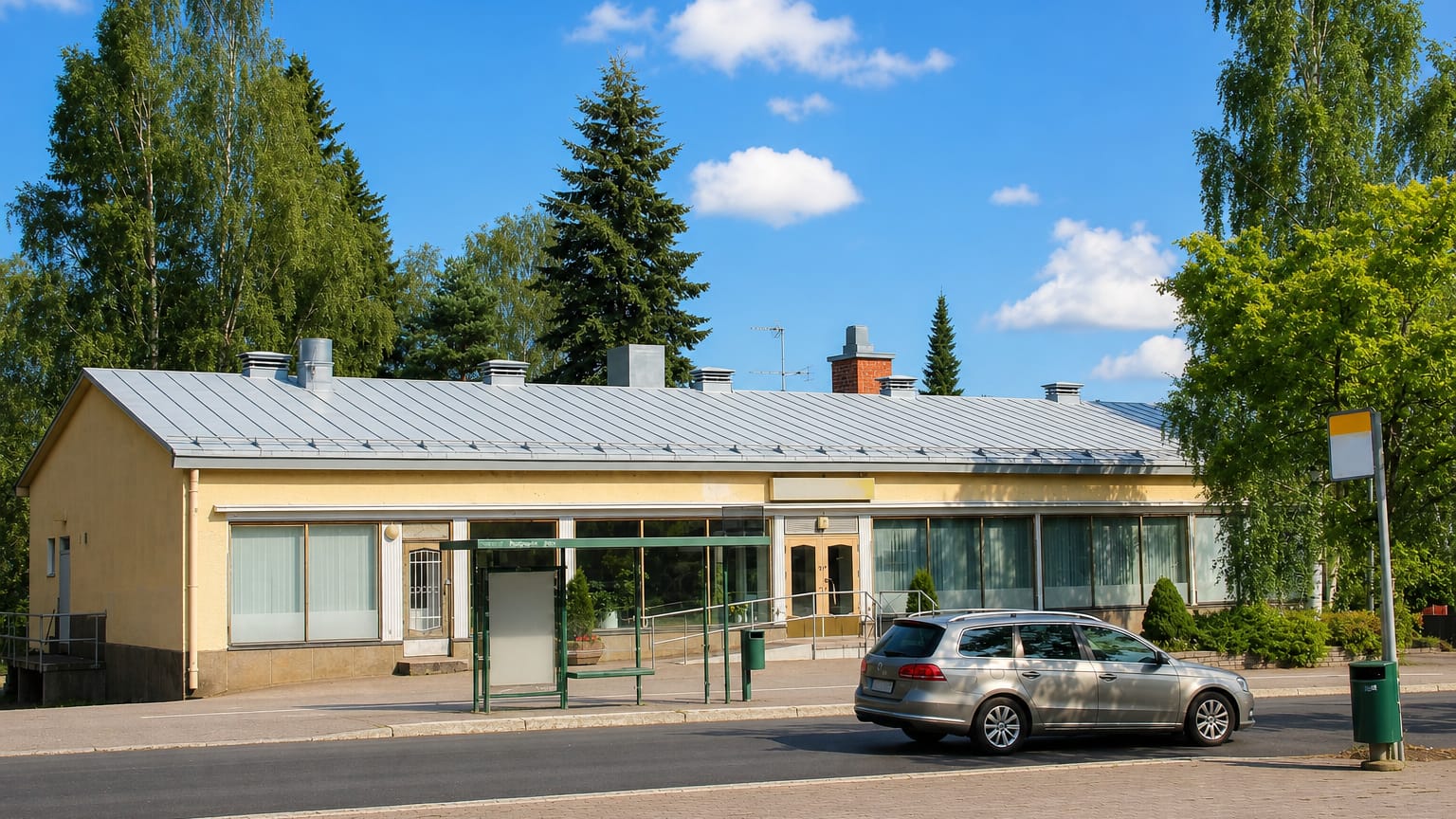 Paloheina's low yellow shopping parade and bus shelter framed by birches in northern Helsinki