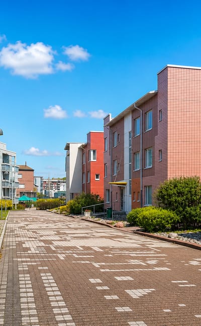 Colourful low-rise apartment blocks lining a paved pedestrian street in Pikku-Huopalahti, Helsinki.