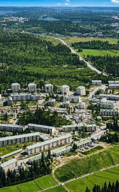 Aerial view of Pohjois-Haaga's white apartment blocks set among forest and green fields in Helsinki, Finland