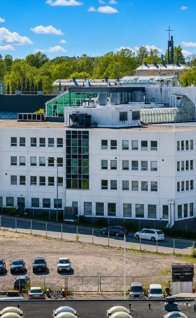 A white modernist office block above a parking area in Roihuvuori, a leafy residential district of eastern Helsinki.