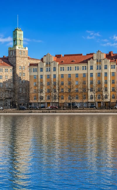 Siltasaari's Jugendstil waterfront in Helsinki reflected in the bay, with a swan on the water
