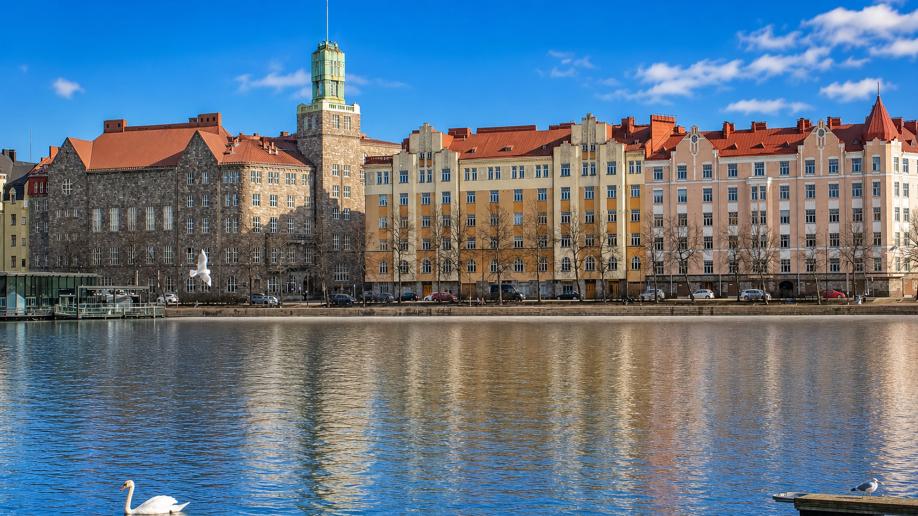 Siltasaari's Jugendstil waterfront in Helsinki reflected in the bay, with a swan on the water