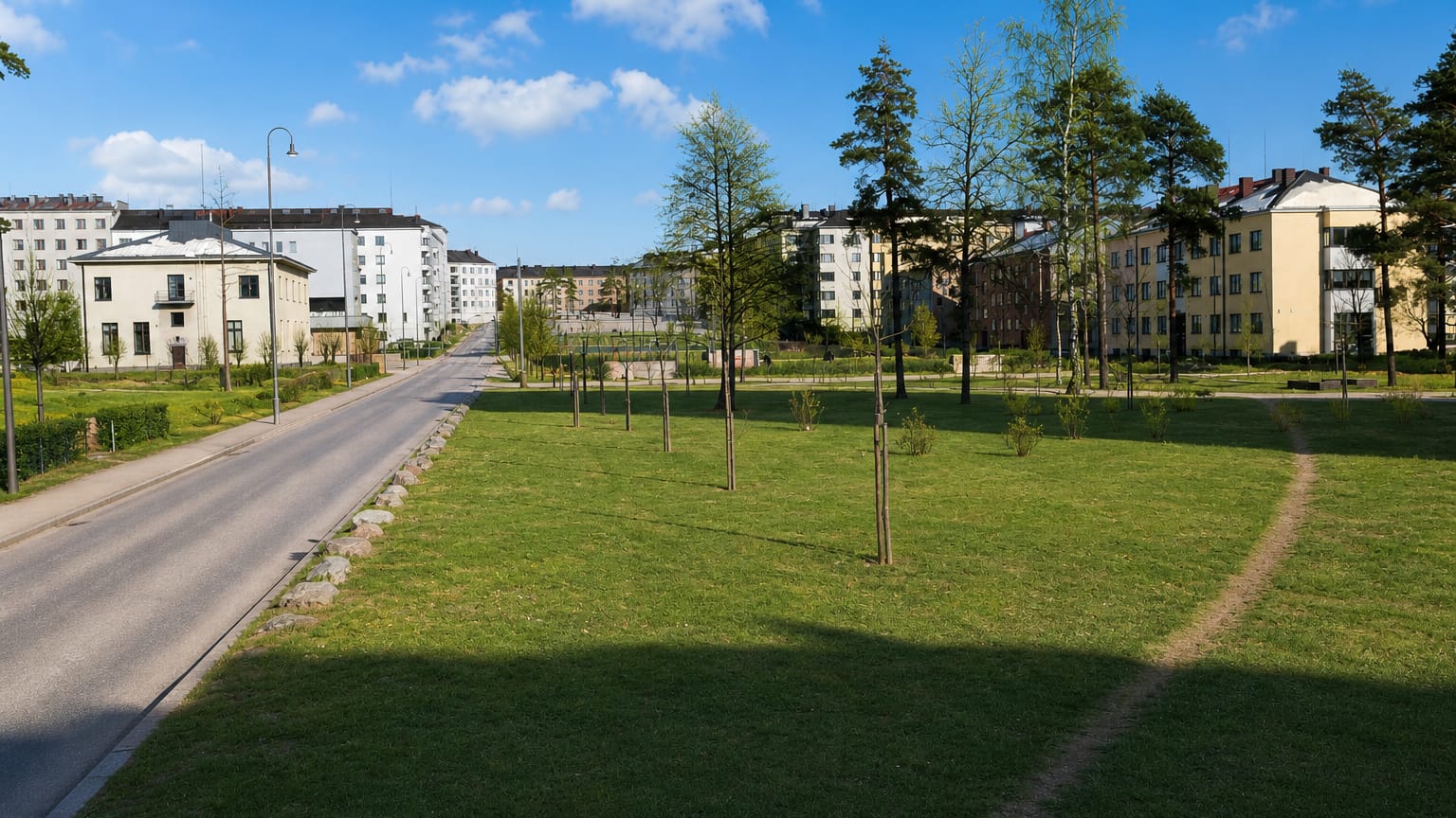 Sunlit park lawn and tree-lined street fronting rows of mid-rise apartment blocks in Taka-Töölö, Helsinki.