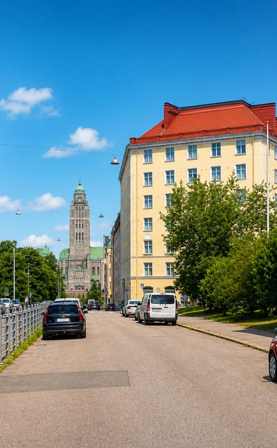 Torkelsbacken street in Helsinki's Kallio, lined with 1920s apartment blocks and Kallio Church tower beyond.