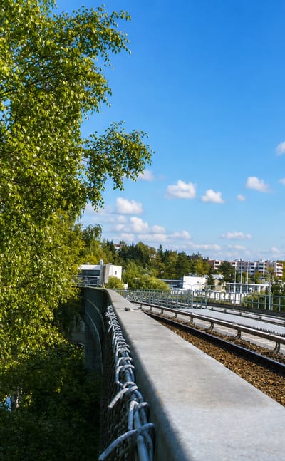 Metro railway on a concrete viaduct beside birch trees and white suburban apartment blocks in Vesala, Helsinki