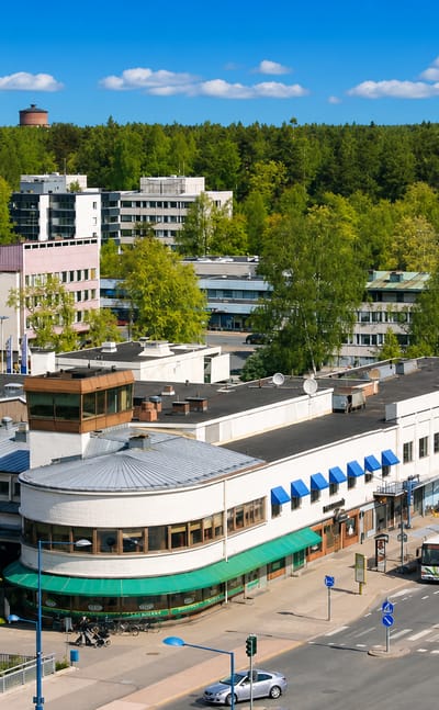 Aerial view of Hyvinge town centre with its triangular white church and water tower above low-rise shops and a local bus.