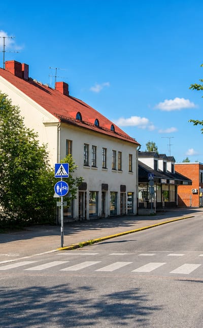 Quiet town-centre street with pastel buildings and a pedestrian crossing in Karkkila, Finland.