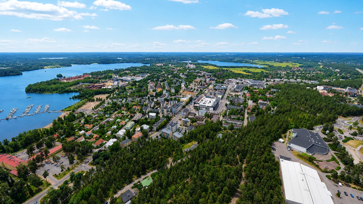 Aerial view of Lohja, Finland, a lakeside town on Lake Lohjanjärvi ringed by forest, with a marina and compact town centre