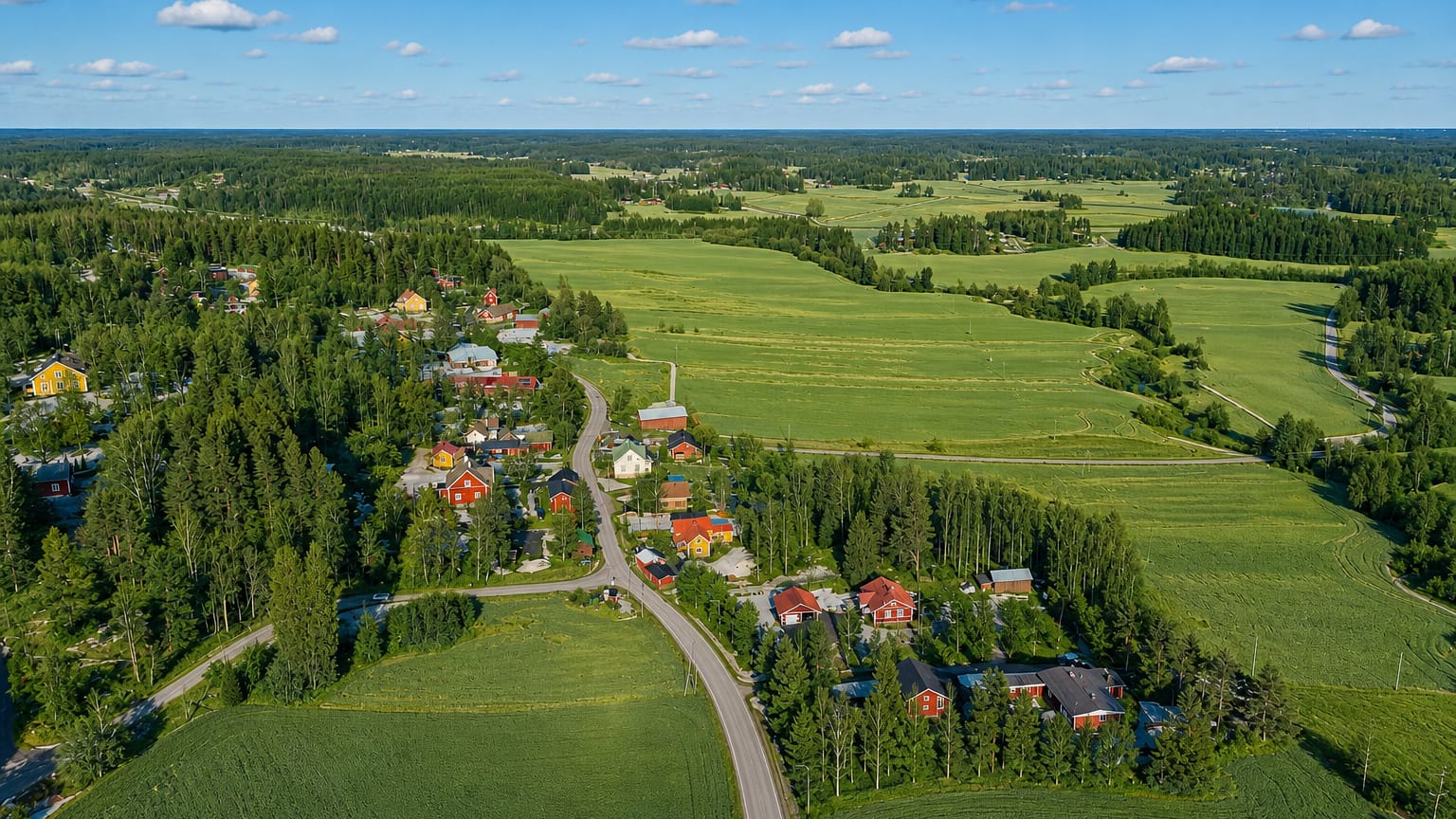 Rural Sibbo village of red wooden houses and a church among green fields and forest in Uusimaa