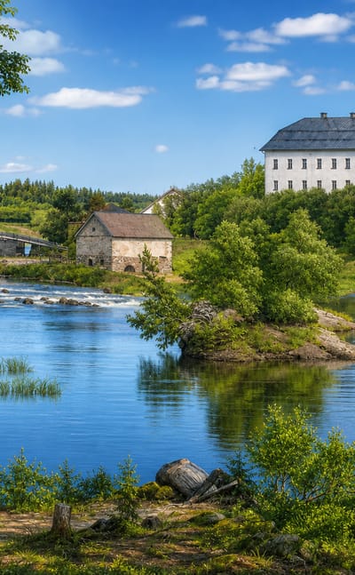 White manor house above the Siuntionjoki river rapids with an old stone mill and bridge in Siuntio, Finland