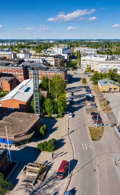 Aerial daytime view over Vantaa, Finland: low-rise brick and white buildings around a central square and tree-lined streets.