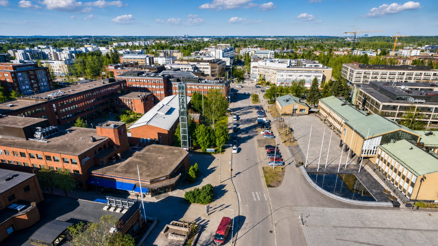 Aerial daytime view over Vantaa, Finland: low-rise brick and white buildings around a central square and tree-lined streets.