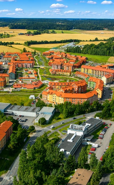 Aerial view of Kartanonkoski, Vantaa, its colorful red-roofed New Urbanist apartment blocks ringed by forest and fields