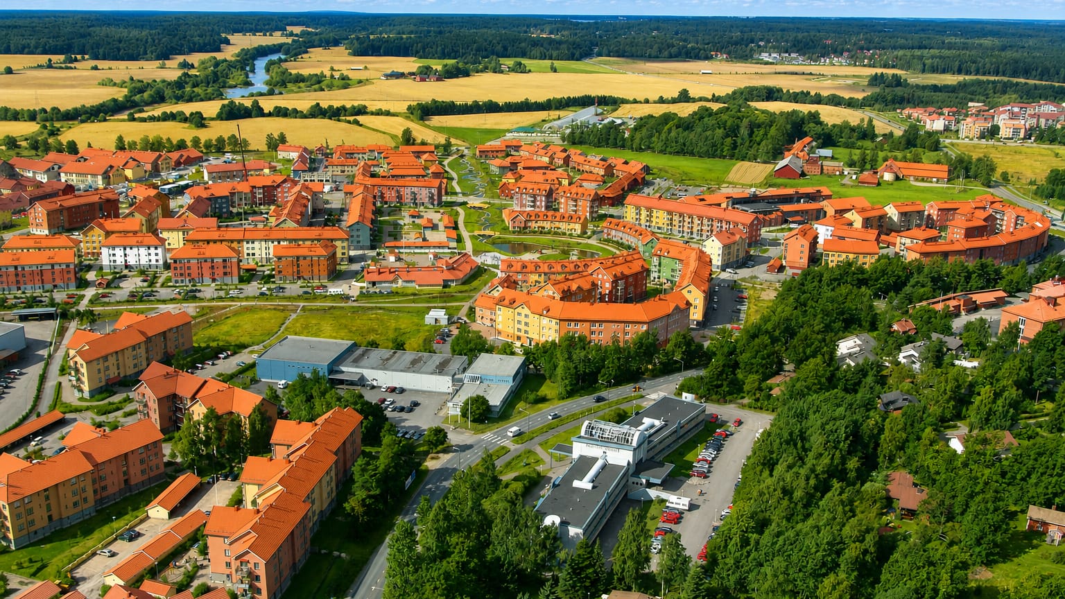 Aerial view of Kartanonkoski, Vantaa, its colorful red-roofed New Urbanist apartment blocks ringed by forest and fields