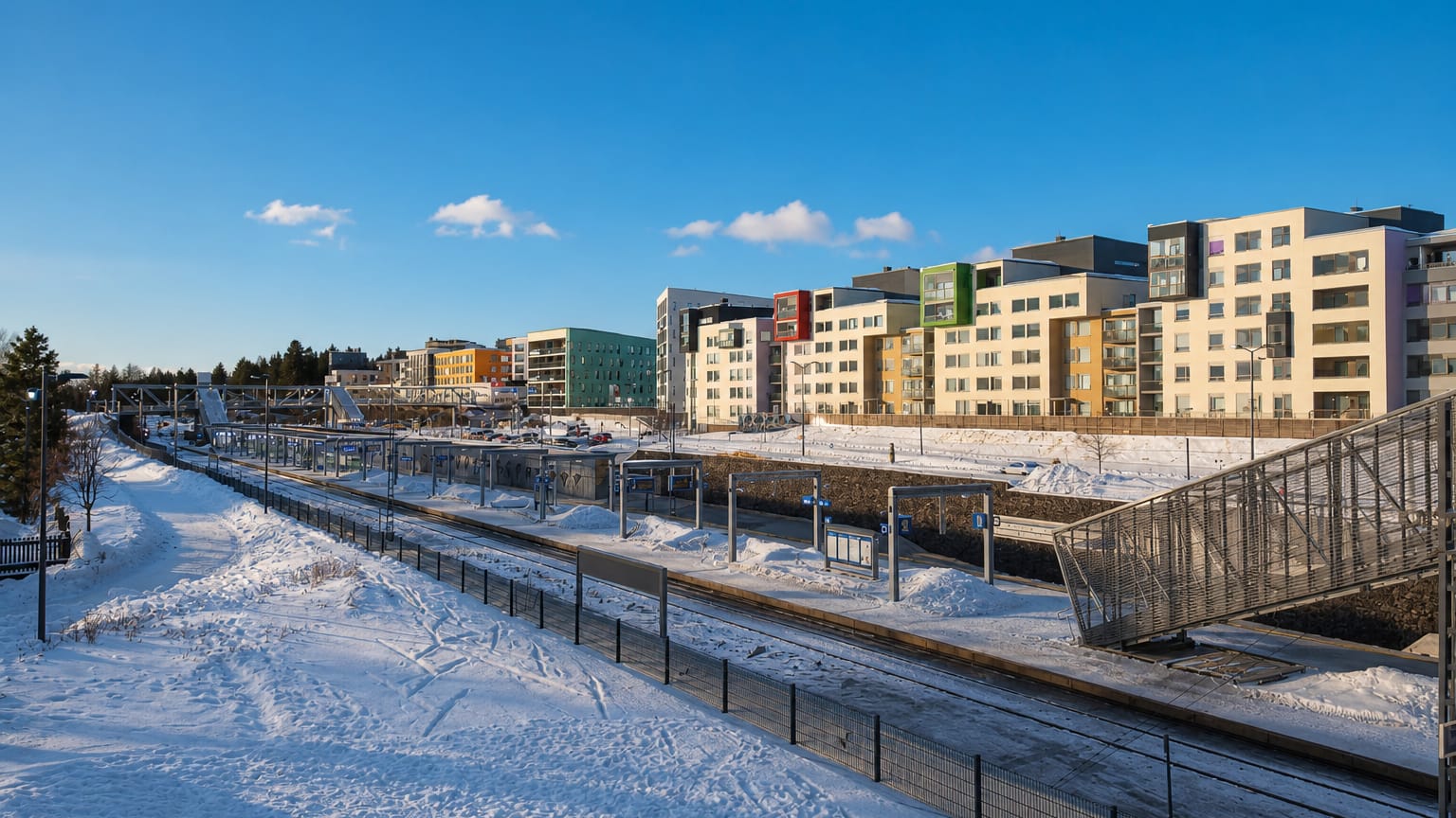 Colourful modern apartment blocks beside Leinelä railway station under snow and clear blue sky, Vantaa, Finland