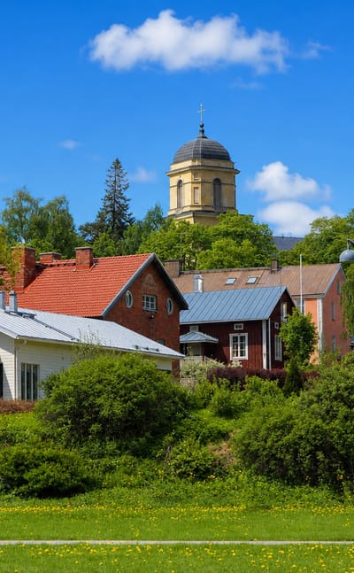 Vihti's domed church tower rising above red and white wooden houses and lush summer greenery, Uusimaa, Finland