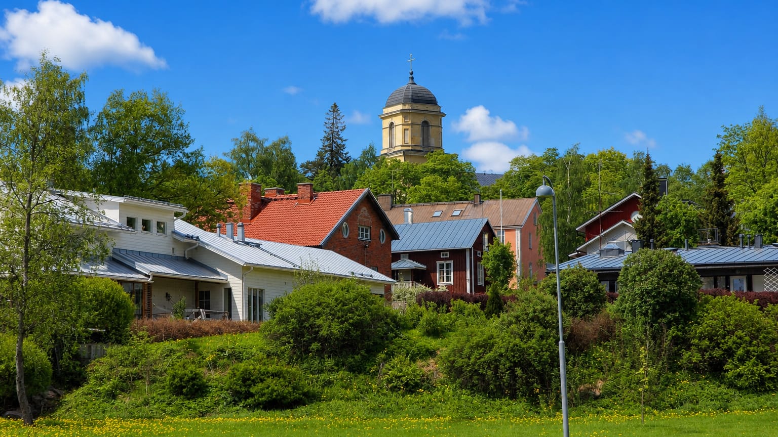 Vihti's domed church tower rising above red and white wooden houses and lush summer greenery, Uusimaa, Finland