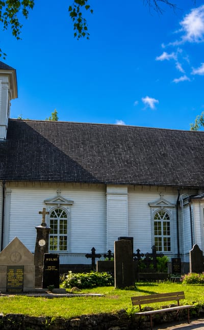 Alastaro's white wooden church with a bell tower rising above its graveyard of headstones and stone crosses.