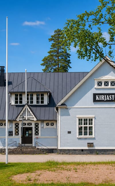 The pale-blue wooden village library, marked Kirjasto, behind birch trees in Kisko, Finland.