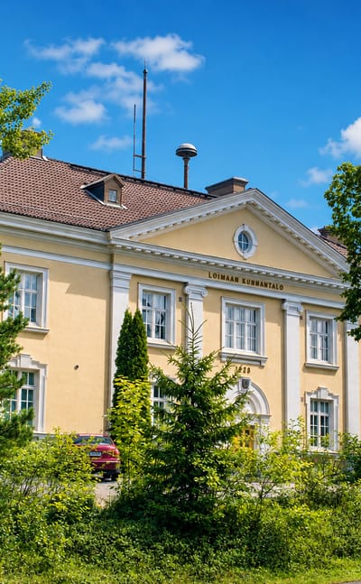 Yellow neoclassical Loimaa municipal hall with columns, its name in the pediment, in Loimaa, Finland.