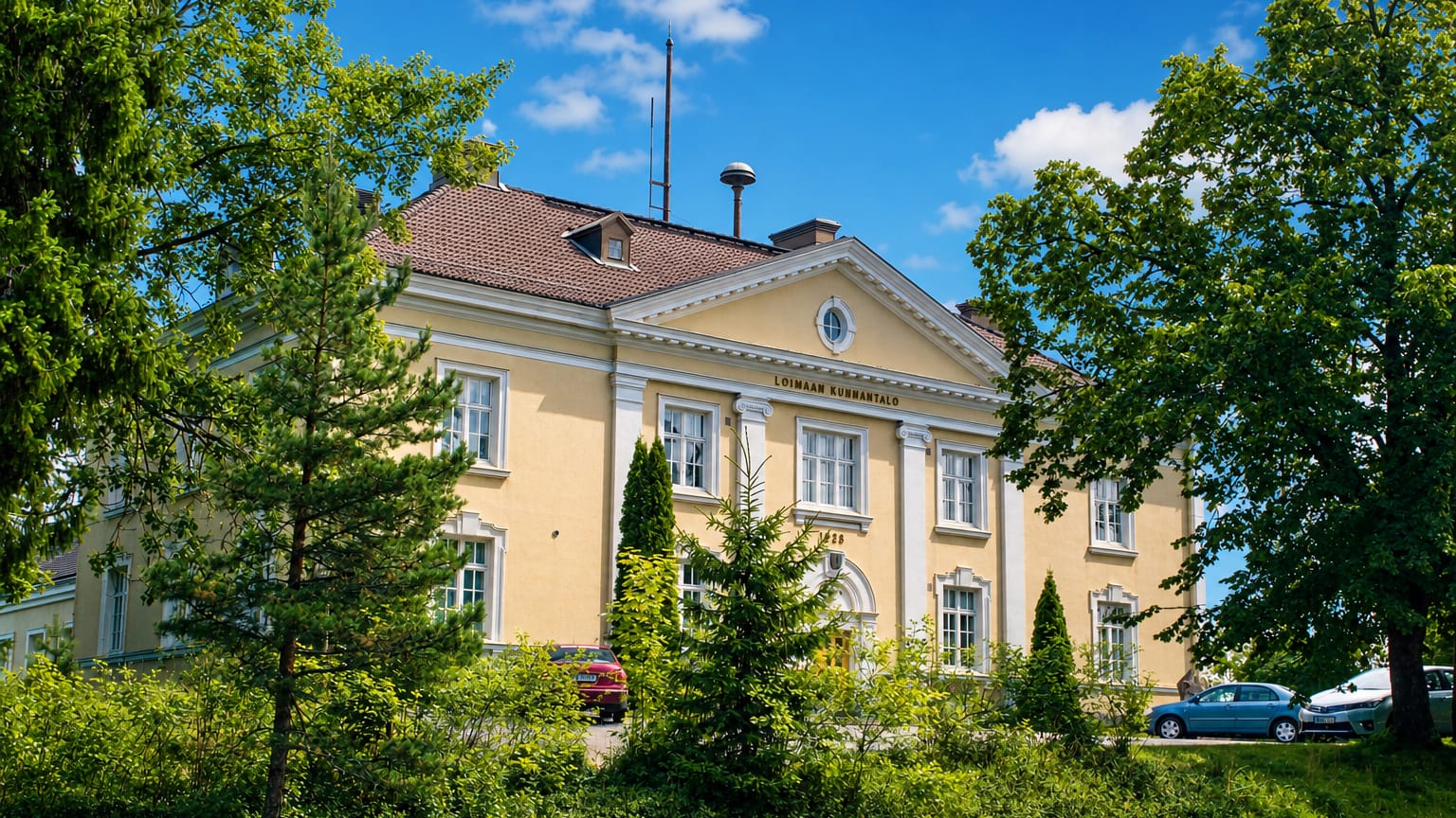 Yellow neoclassical Loimaa municipal hall with columns, its name in the pediment, in Loimaa, Finland.