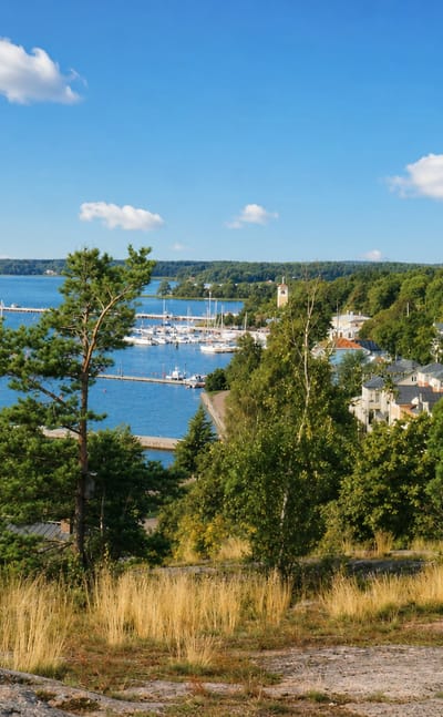 Naantali's old town and guest marina below a wooded hilltop, the medieval church tower rising above the archipelago shore.