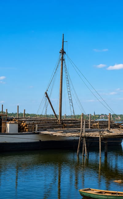 Traditional wooden sailing vessel moored at a timber jetty in the calm archipelago waters of Taivassalo, Finland.