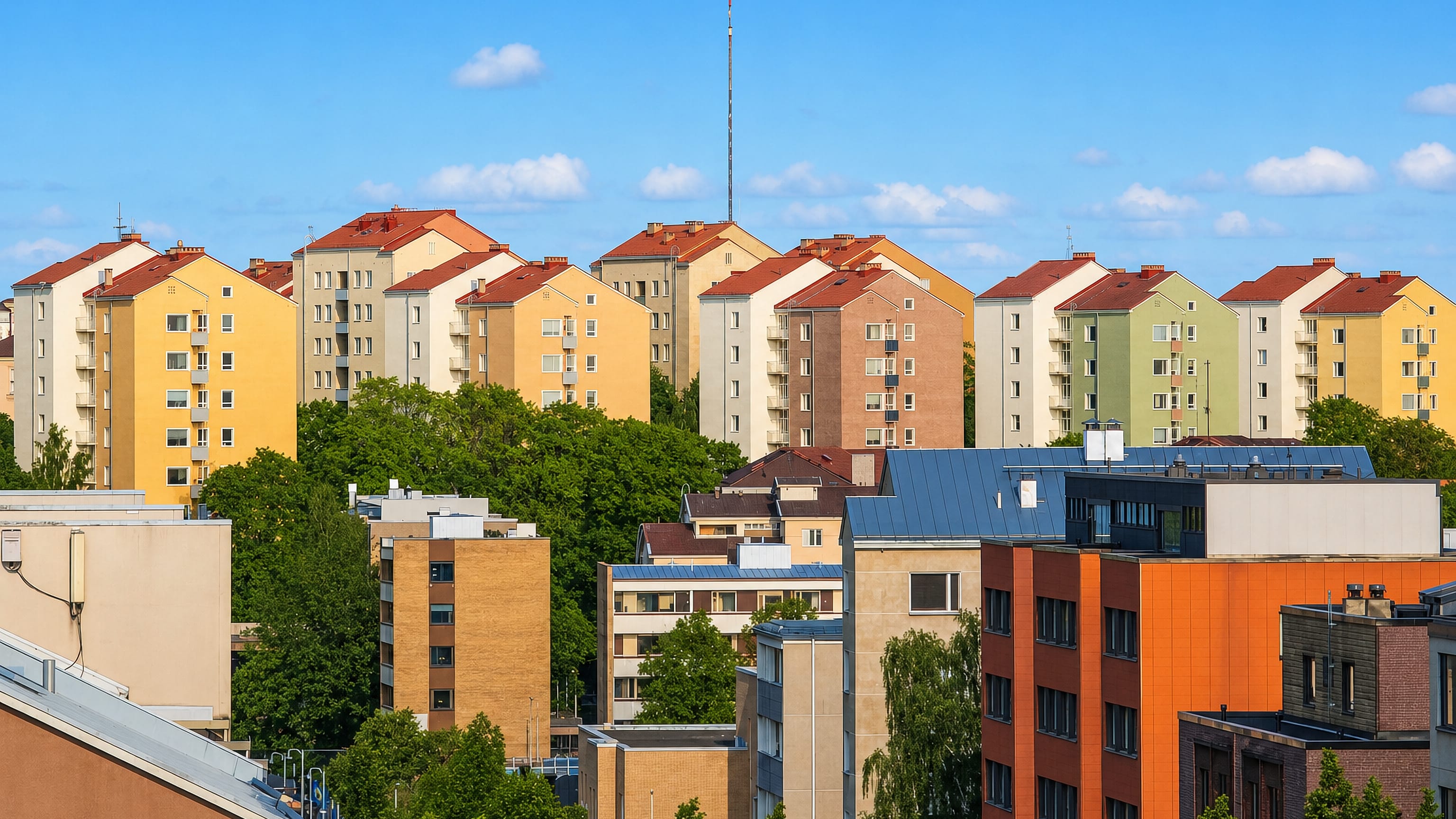 Pastel post-war apartment blocks with red roofs in III kaupunginosa, Turku, seen above the treetops.