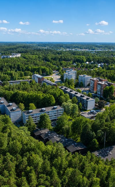 Aerial view of apartment blocks in pine forest with the sea and archipelago beyond, Ispoinen, Turku.
