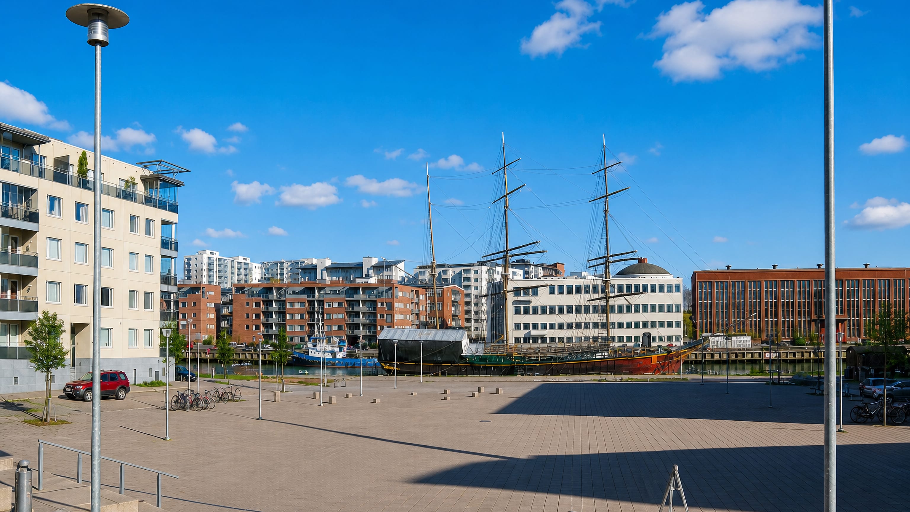 Turku's Itäranta waterfront with a moored tall ship, brick apartment blocks and a wide riverside plaza.
