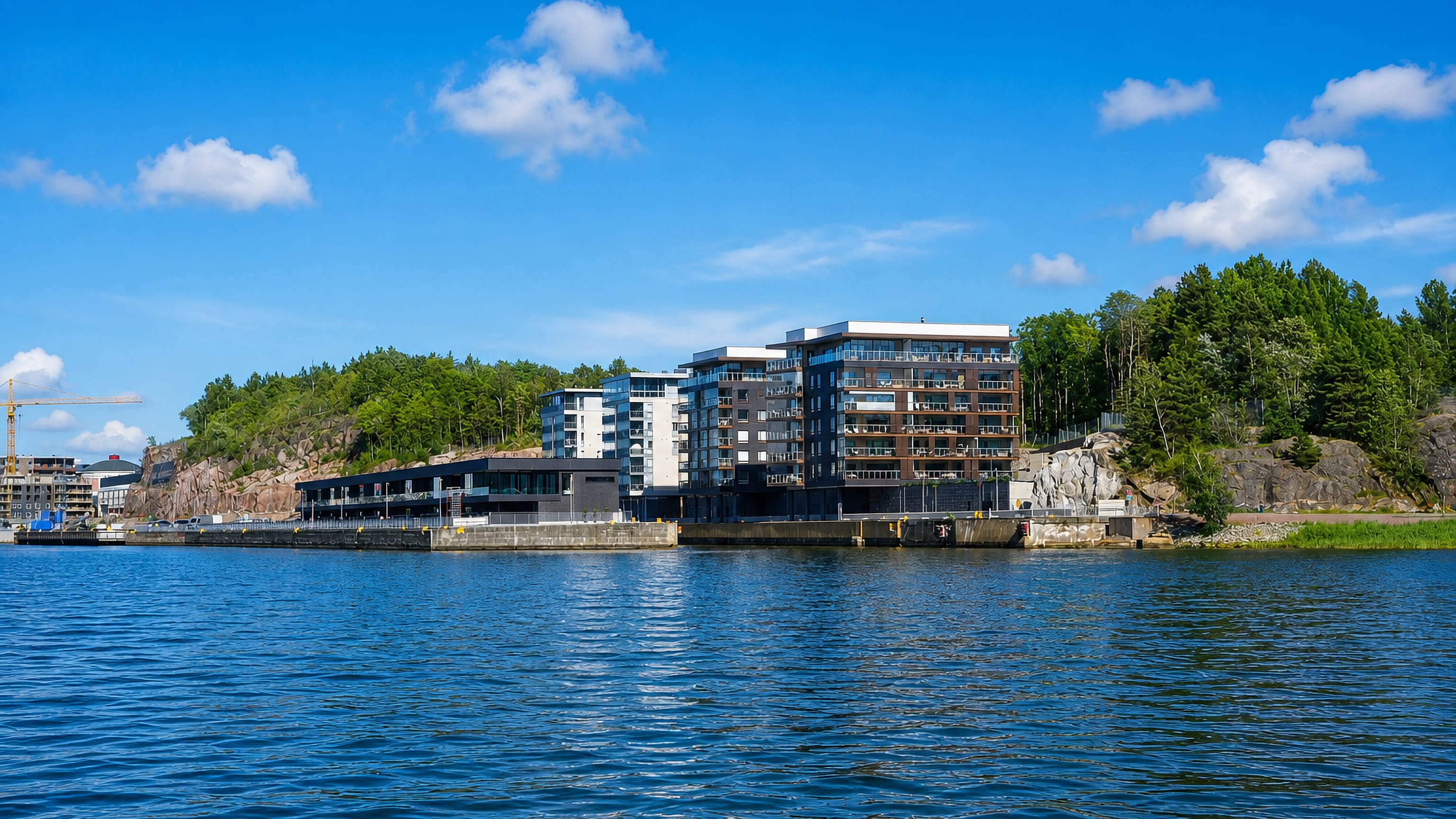 Waterfront apartment blocks on the rocky wooded slope of Korppolaismäki, seen across the water in Turku.
