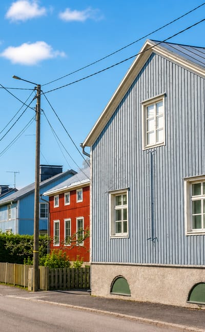 Row of painted wooden houses with metal roofs along a quiet street in Mäntymäki, Turku.