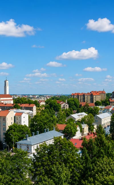 Red-tiled rooftops and the white church tower of Martti, Turku, seen across the district's leafy blocks.