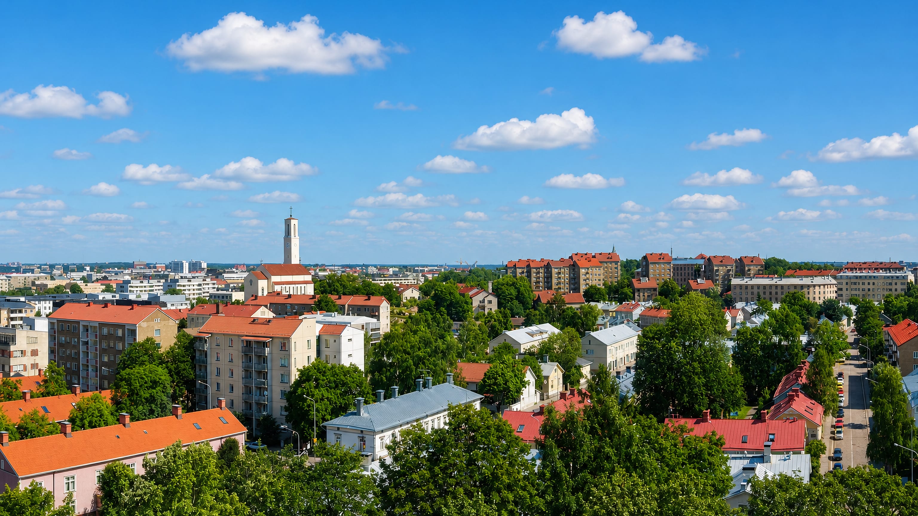 Red-tiled rooftops and the white church tower of Martti, Turku, seen across the district's leafy blocks.
