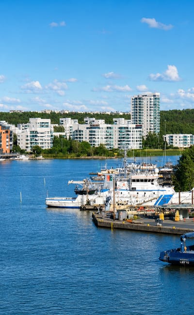 Waterfront apartment blocks and moored vessels across the bay at Pihlajaniemi, Turku