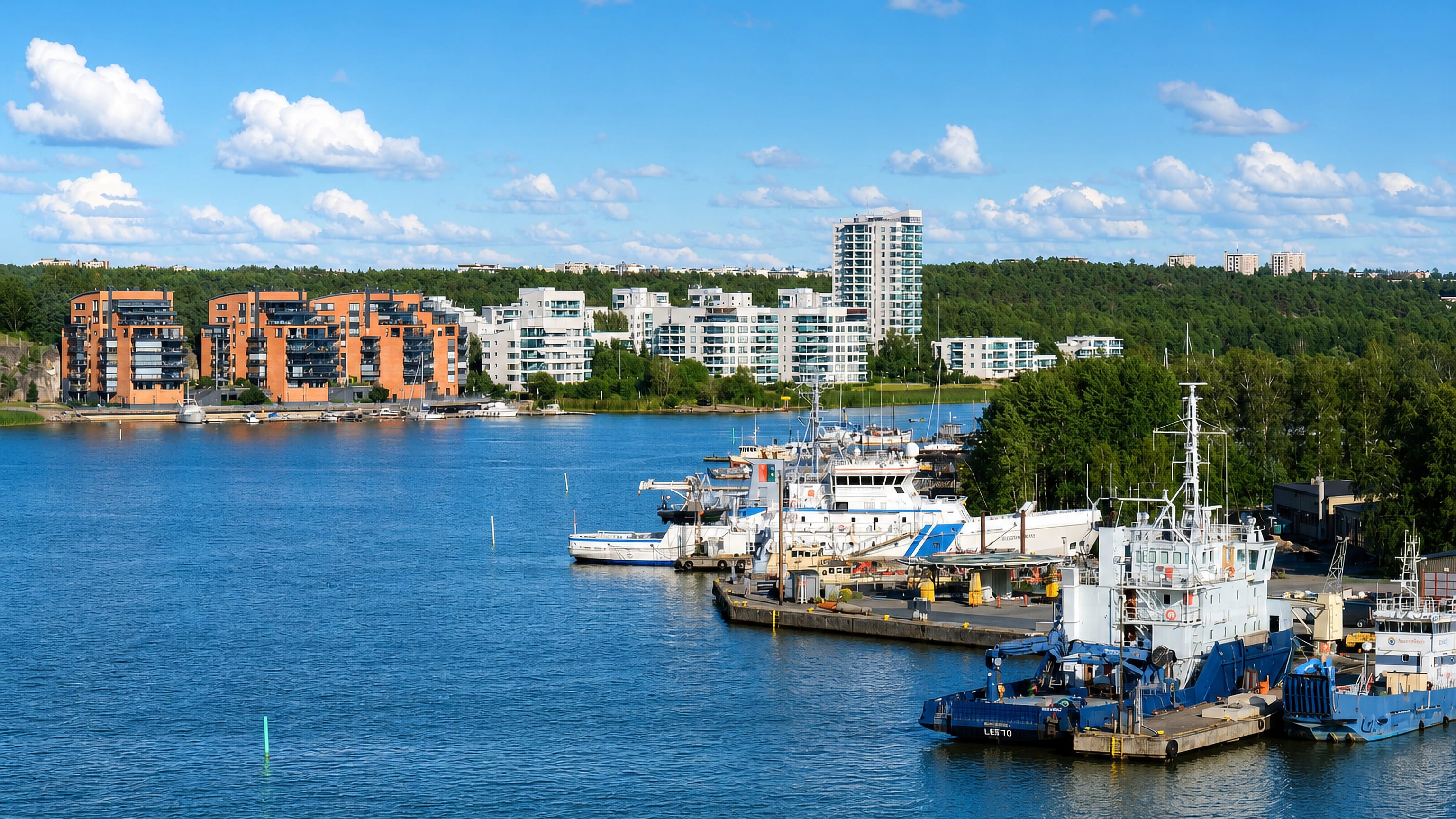 Waterfront apartment blocks and moored vessels across the bay at Pihlajaniemi, Turku