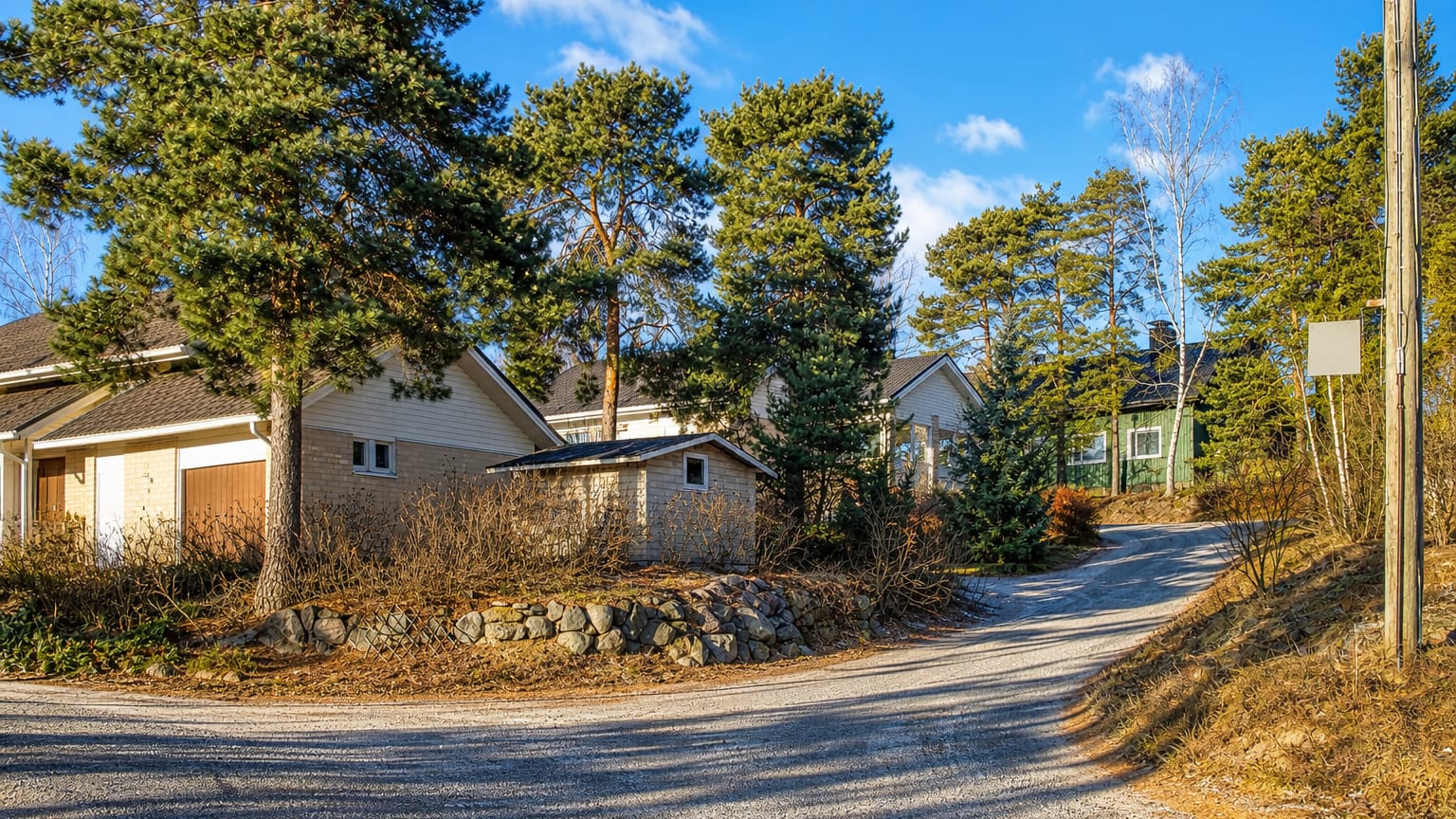 Gravel lane curving past detached wooden houses and pines in Pitkämäki, Turku.
