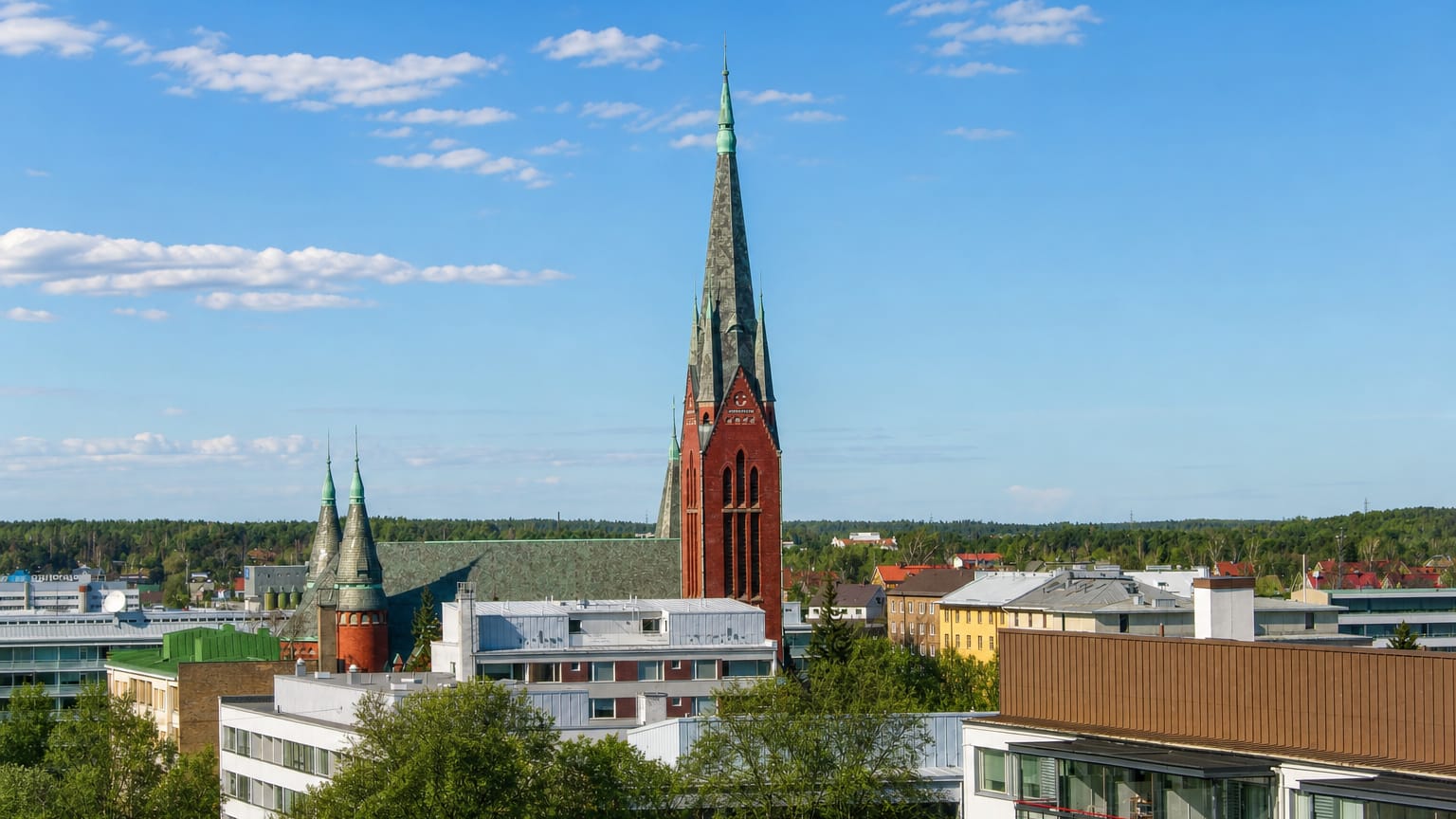 Red-brick neo-Gothic church spire rising above apartment blocks and leafy streets in the Port Arthur district of Turku, Finland.