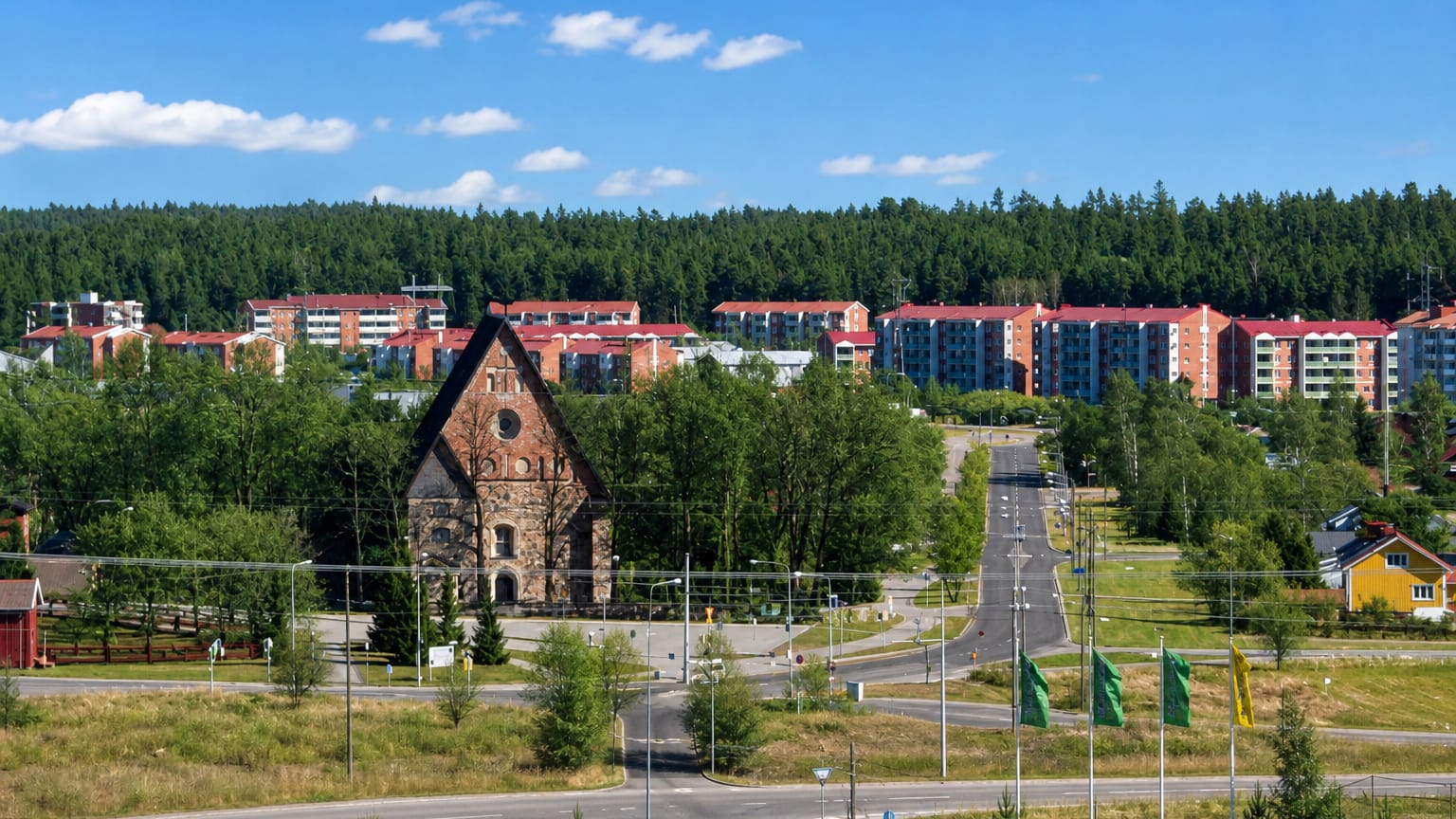 Greystone medieval church at Rantamaki in Turku, framed by red-brick apartment blocks and pine forest