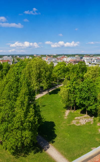Leafy Samppalinna park with the Turku skyline and cathedral tower rising beyond