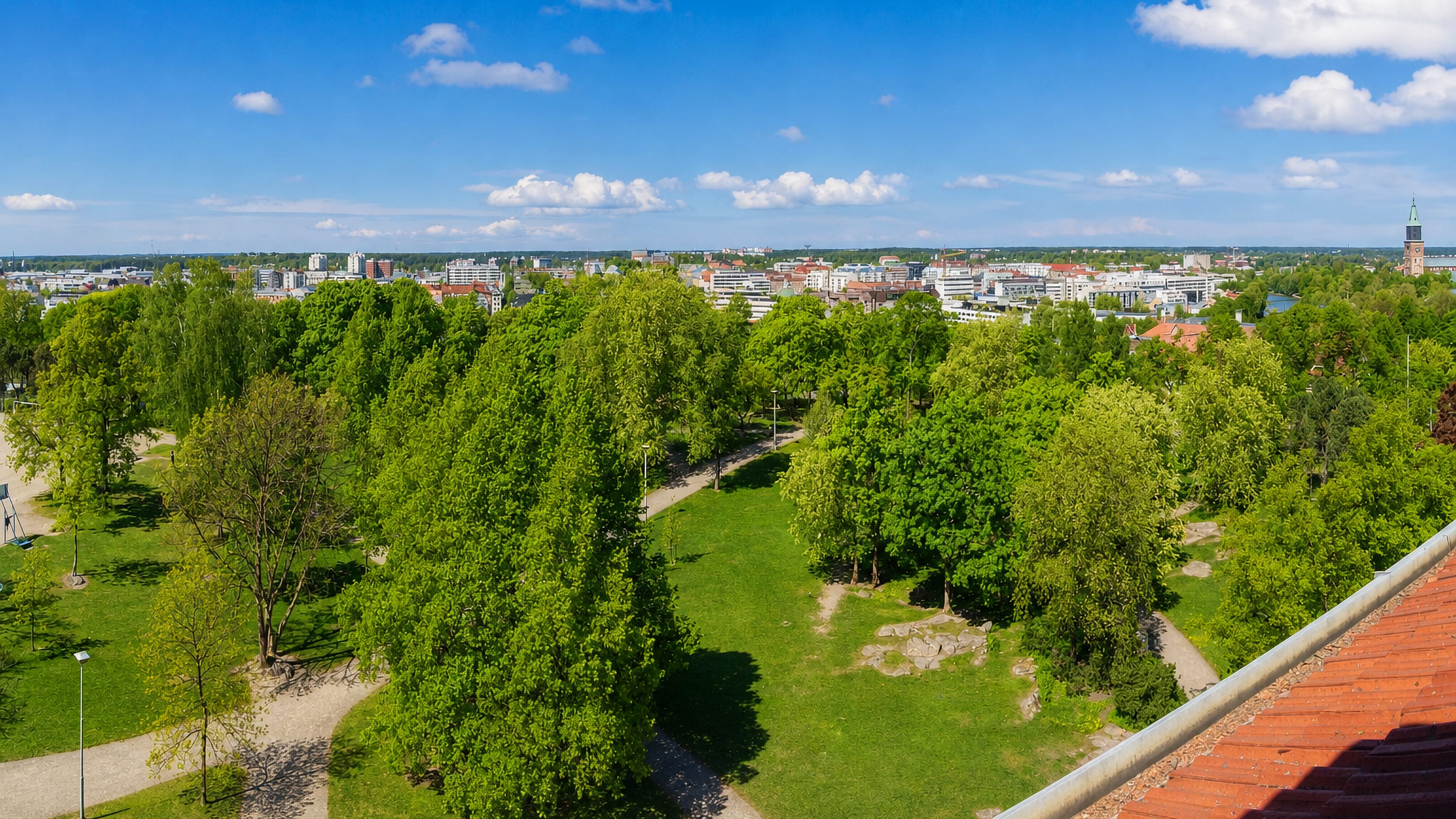 Leafy Samppalinna park with the Turku skyline and cathedral tower rising beyond