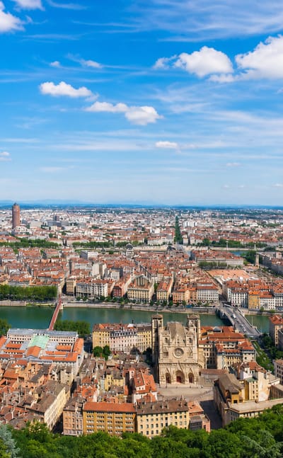 Panorama of Lyon from Fourviere over the old town, the Saone river and its bridges under a blue sky.