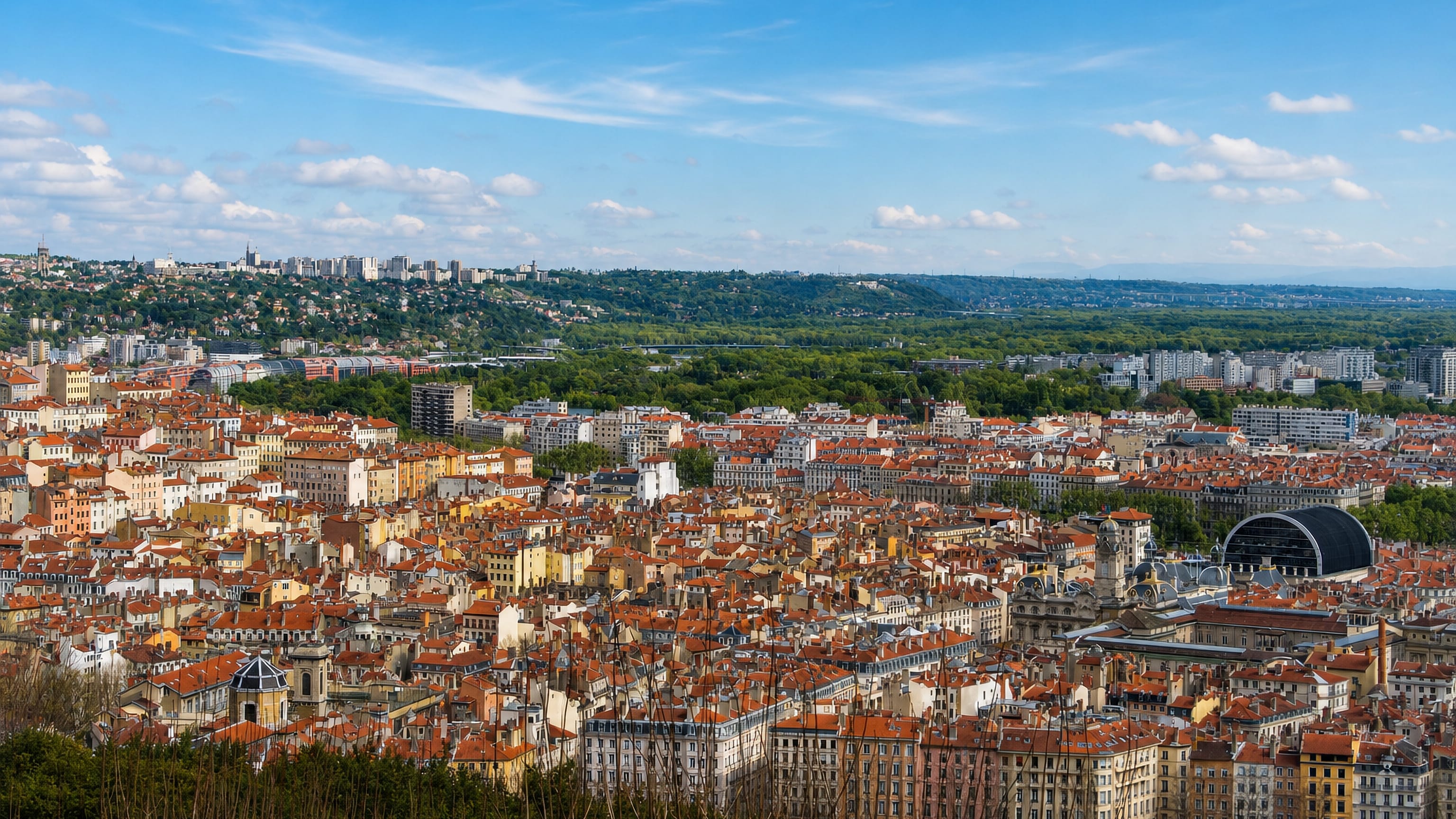 Rooftops of Lyon 01 seen from Fourvière, with the Opéra Nouvel's black barrel roof and the valley beyond.