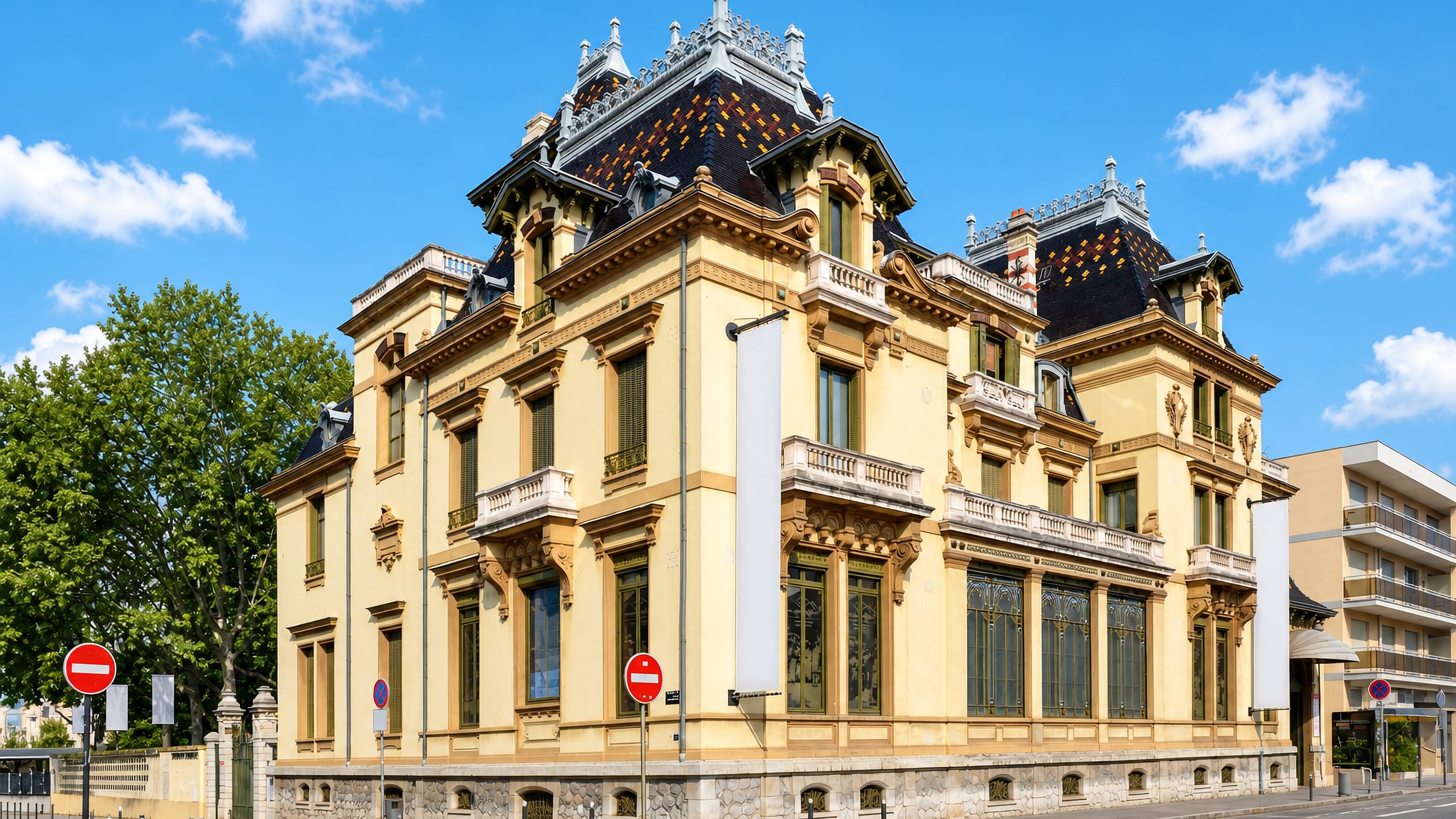 Ornate 19th-century mansion with a slate mansard roof at a street corner in Lyon's 8th arrondissement.