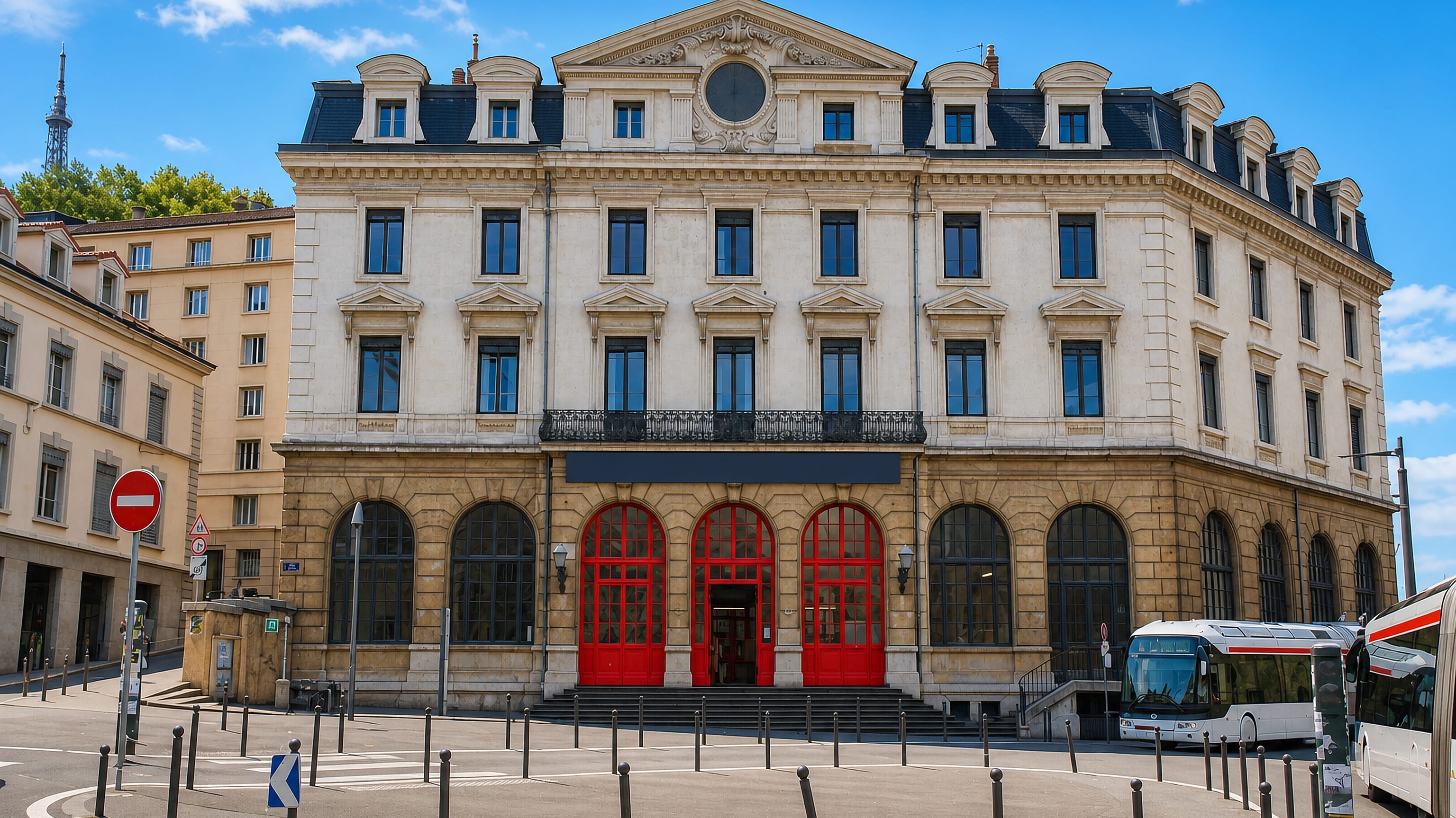 Grand stone facade with red arched doors in Vieux Lyon, the Fourvière metal tower on the hill above
