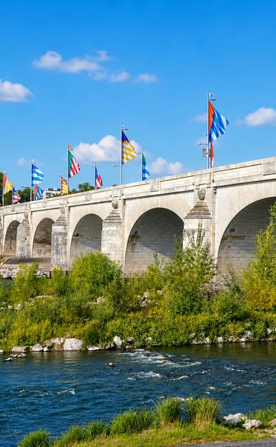 Flag-lined stone arch bridge over the Loire river at Tours, France, on a sunny day